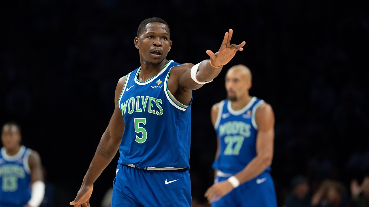 Minnesota Timberwolves guard Anthony Edwards holds up three fingers on each hand after making a shot, with teammates behind him.