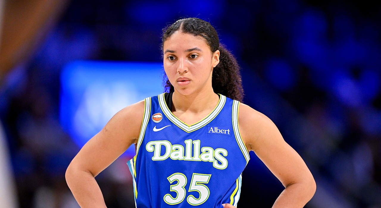 Wings guard Azzi Fudd stands with her hands on her hips in a blue Dallas jersey.