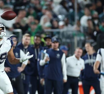 Dallas Cowboys tight end Brevyn Spann-Ford tracks a pass with his eyes as the ball drops toward his hands near the sideline.