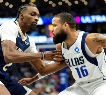 Dallas Mavericks forward Caleb Martin protects the ball with his right hand as New Orleans Pelicans forward Herbert Jones guards him.