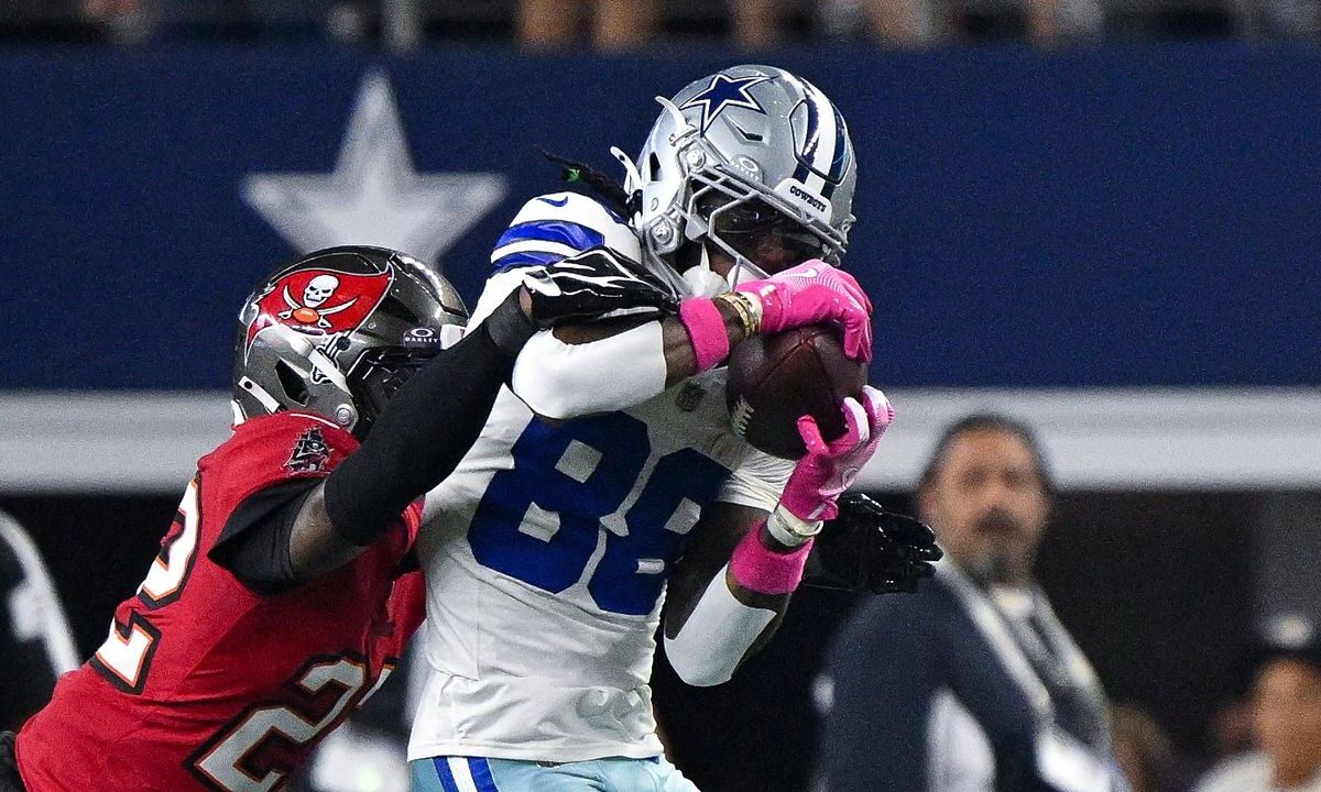 Dallas Cowboys wide receiver CeeDee Lamb secures a catch as Tampa Bay Buccaneers cornerback Keionte Scott reaches over his shoulder.