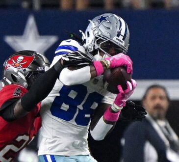 Dallas Cowboys wide receiver CeeDee Lamb secures a catch as Tampa Bay Buccaneers cornerback Keionte Scott reaches over his shoulder.