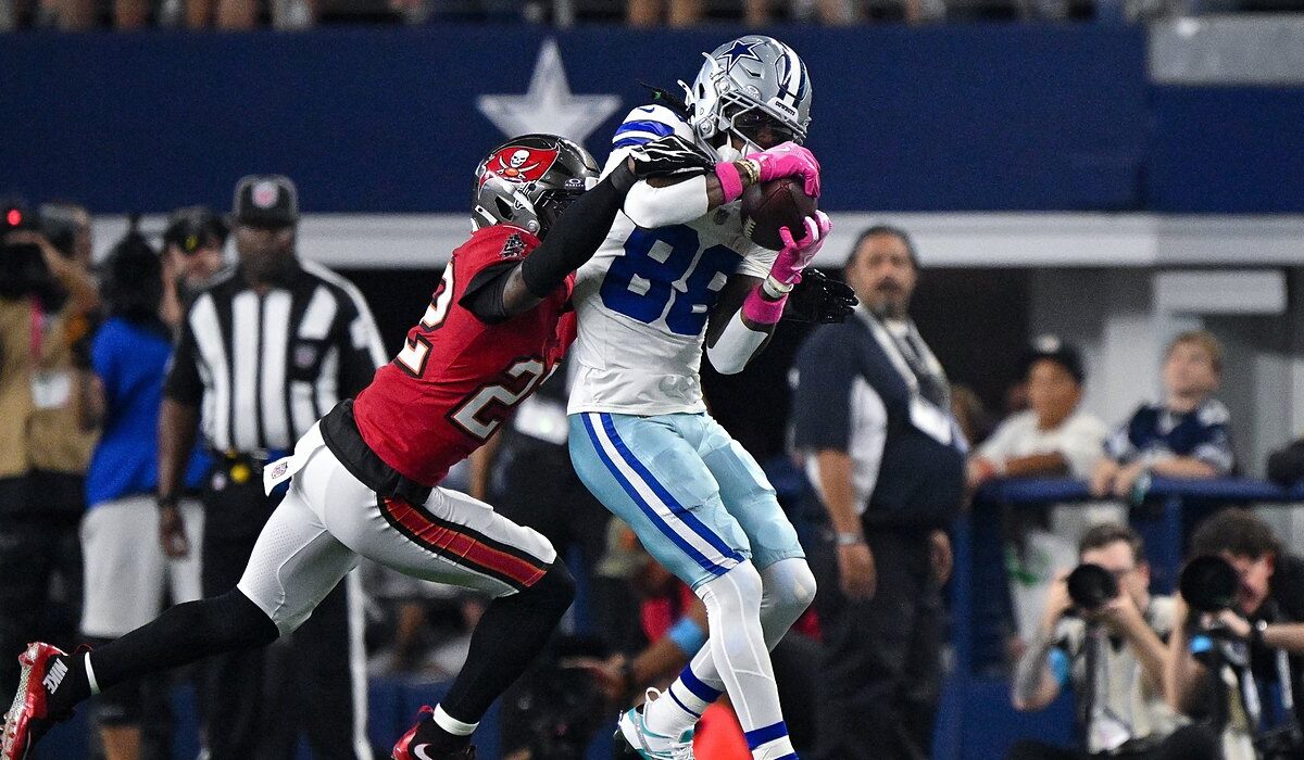 Cowboys wide receiver CeeDee Lamb secures a catch as Buccaneers cornerback Keionte Scott wraps him from behind.