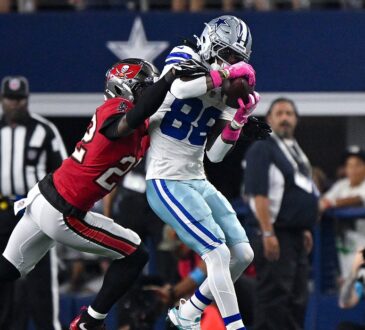 Cowboys wide receiver CeeDee Lamb secures a catch as Buccaneers cornerback Keionte Scott wraps him from behind.