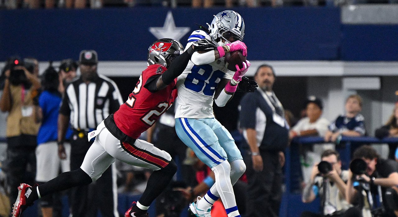 Cowboys wide receiver CeeDee Lamb secures a catch as Buccaneers cornerback Keionte Scott wraps him from behind.