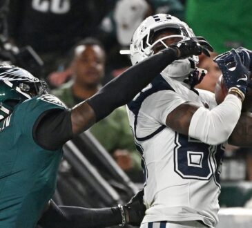 Dallas Cowboys wide receiver CeeDee Lamb hauls in a pass against his chest as an Eagles cornerback reaches across his face mask.