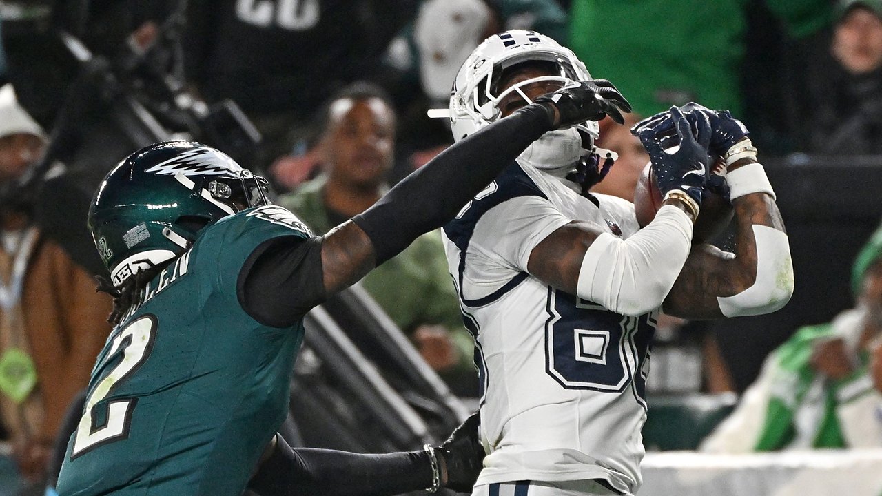 Dallas Cowboys wide receiver CeeDee Lamb hauls in a pass against his chest as an Eagles cornerback reaches across his face mask.