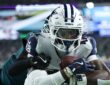Dallas Cowboys wide receiver CeeDee Lamb secures the ball against his chest as an Eagles cornerback wraps him up from behind.