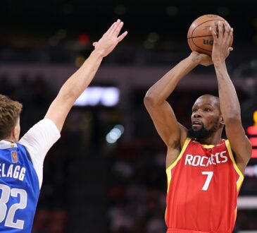 Mavericks forward Cooper Flagg raises his arms to contest a jump shot by Rockets forward Kevin Durant.