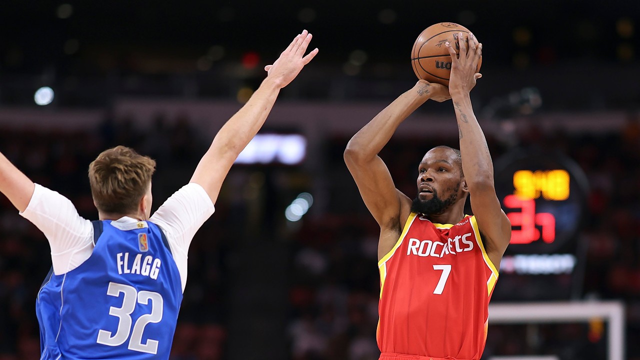 Mavericks forward Cooper Flagg raises his arms to contest a jump shot by Rockets forward Kevin Durant.