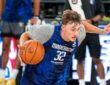 Mavericks forward Cooper Flagg dribbles hard to his right during practice, with an NBA China Games sign behind him.