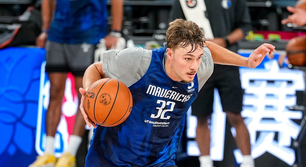 Mavericks forward Cooper Flagg dribbles hard to his right during practice, with an NBA China Games sign behind him.