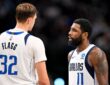 Dallas Mavericks forward Cooper Flagg, seen from behind, talks with guard Kyrie Irving on the court during a game.