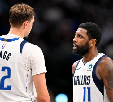 Dallas Mavericks forward Cooper Flagg, seen from behind, talks with guard Kyrie Irving on the court during a game.