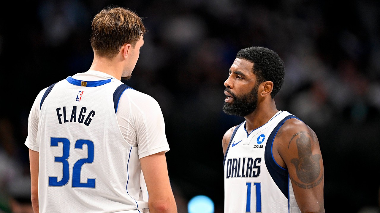 Dallas Mavericks forward Cooper Flagg, seen from behind, talks with guard Kyrie Irving on the court during a game.
