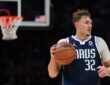Dallas Mavericks forward Cooper Flagg dribbles the ball up the court with a basket blurred in the background.
