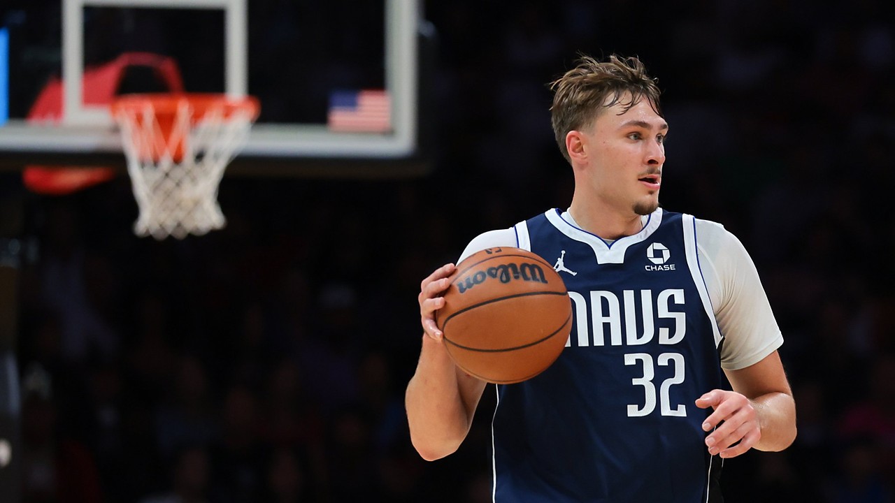 Dallas Mavericks forward Cooper Flagg dribbles the ball up the court with a basket blurred in the background.
