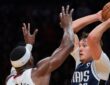 Dallas Mavericks forward Cooper Flagg holds the ball high over his head as Miami Heat center Bam Adebayo reaches up to defend.