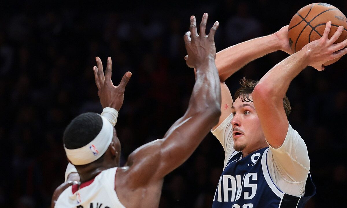 Dallas Mavericks forward Cooper Flagg holds the ball high over his head as Miami Heat center Bam Adebayo reaches up to defend.