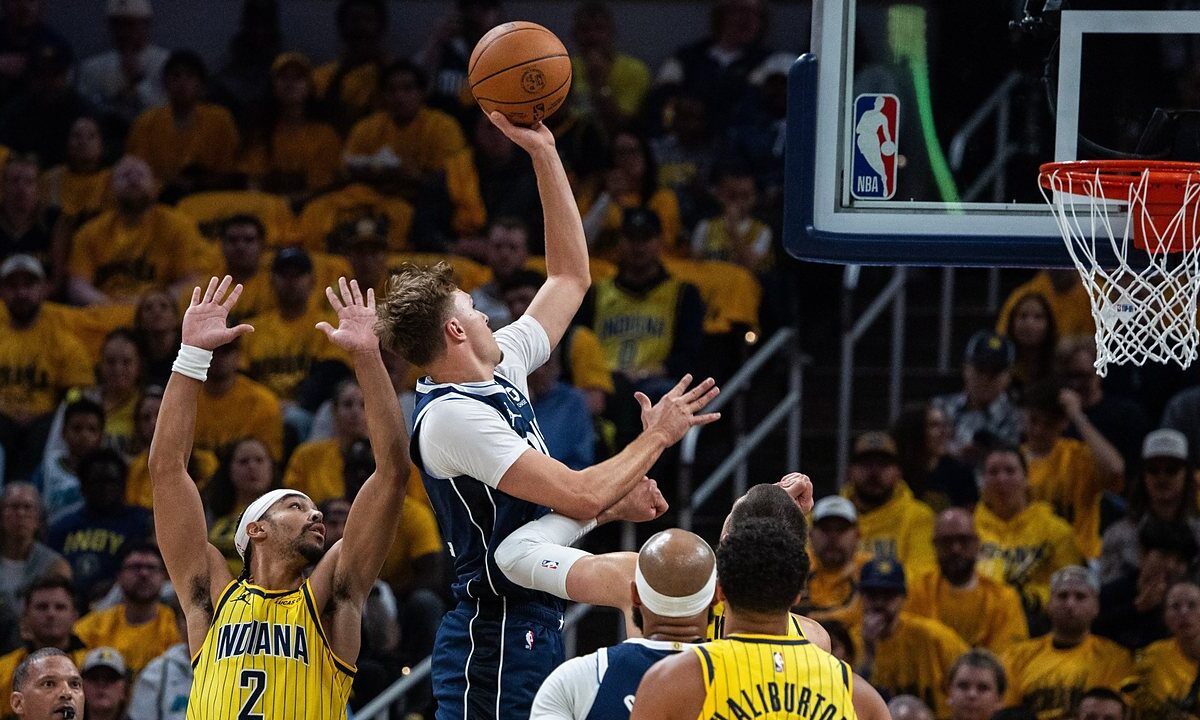Dallas Mavericks forward Cooper Flagg rises for a one-handed shot as Indiana Pacers guard Andrew Nembhard contests with both hands up.