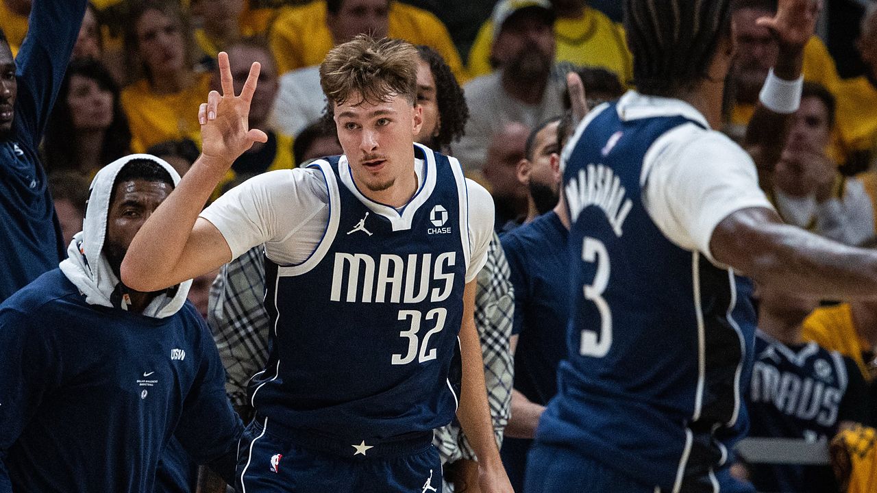 Dallas Mavericks forward Cooper Flagg holds up three fingers as he runs back up the court in front of the Mavericks bench.