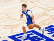 Mavericks forward Cooper Flagg dribbles up the court over Chinese characters painted on the floor.
