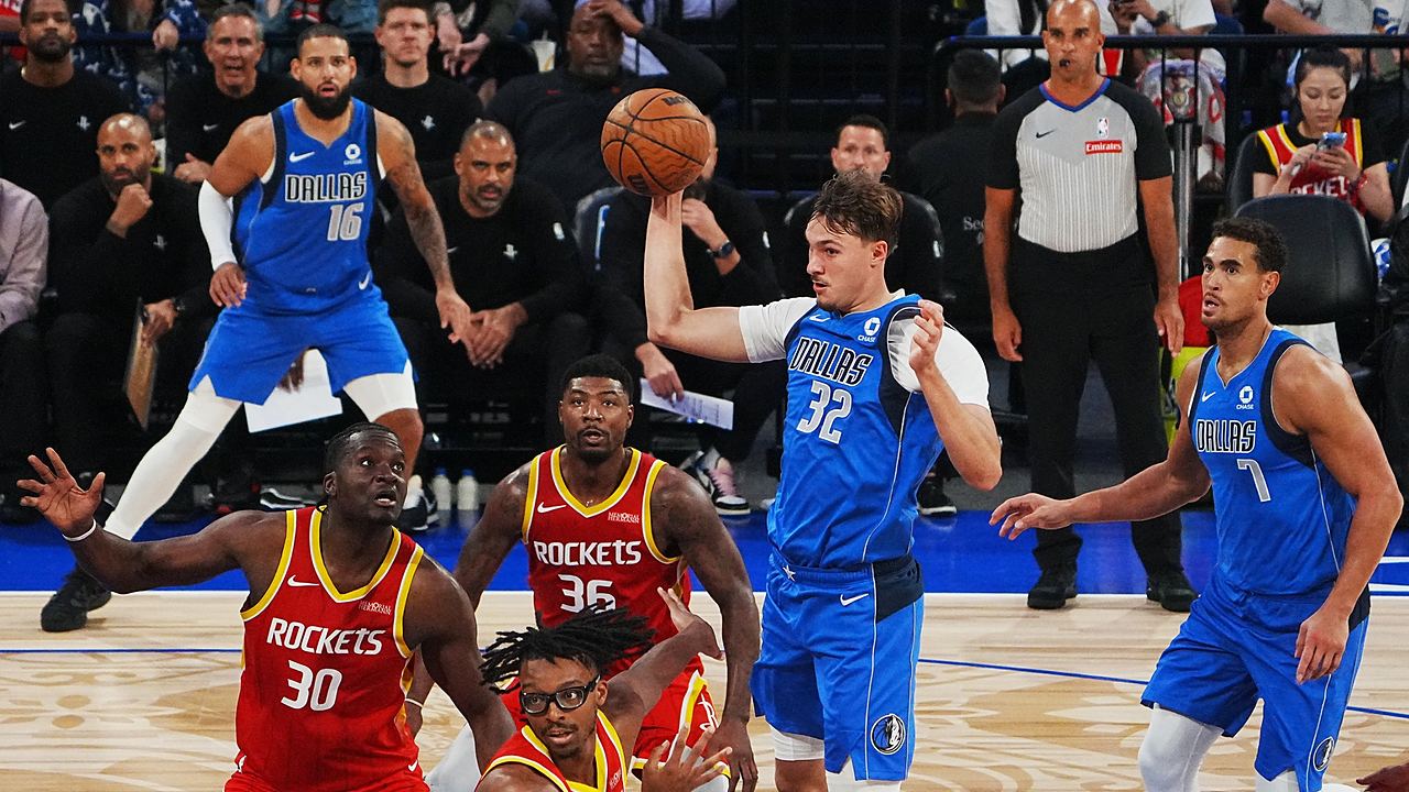 Dallas Mavericks forward Cooper Flagg pulls in a pass with one hand above a group of Houston Rockets players.