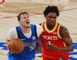 Mavericks forward Cooper Flagg grimaces as he drives with the ball while Rockets guard Amen Thompson defends.