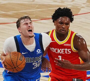 Mavericks forward Cooper Flagg grimaces as he drives with the ball while Rockets guard Amen Thompson defends.