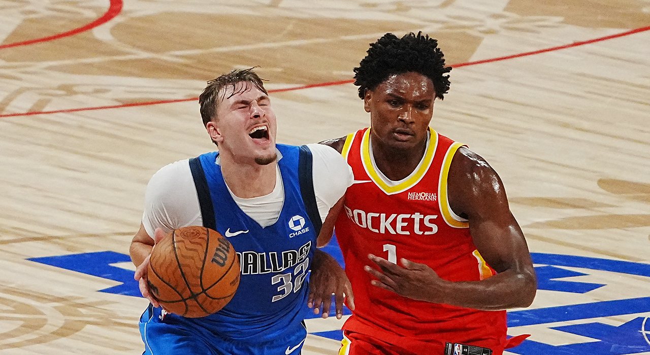Mavericks forward Cooper Flagg grimaces as he drives with the ball while Rockets guard Amen Thompson defends.