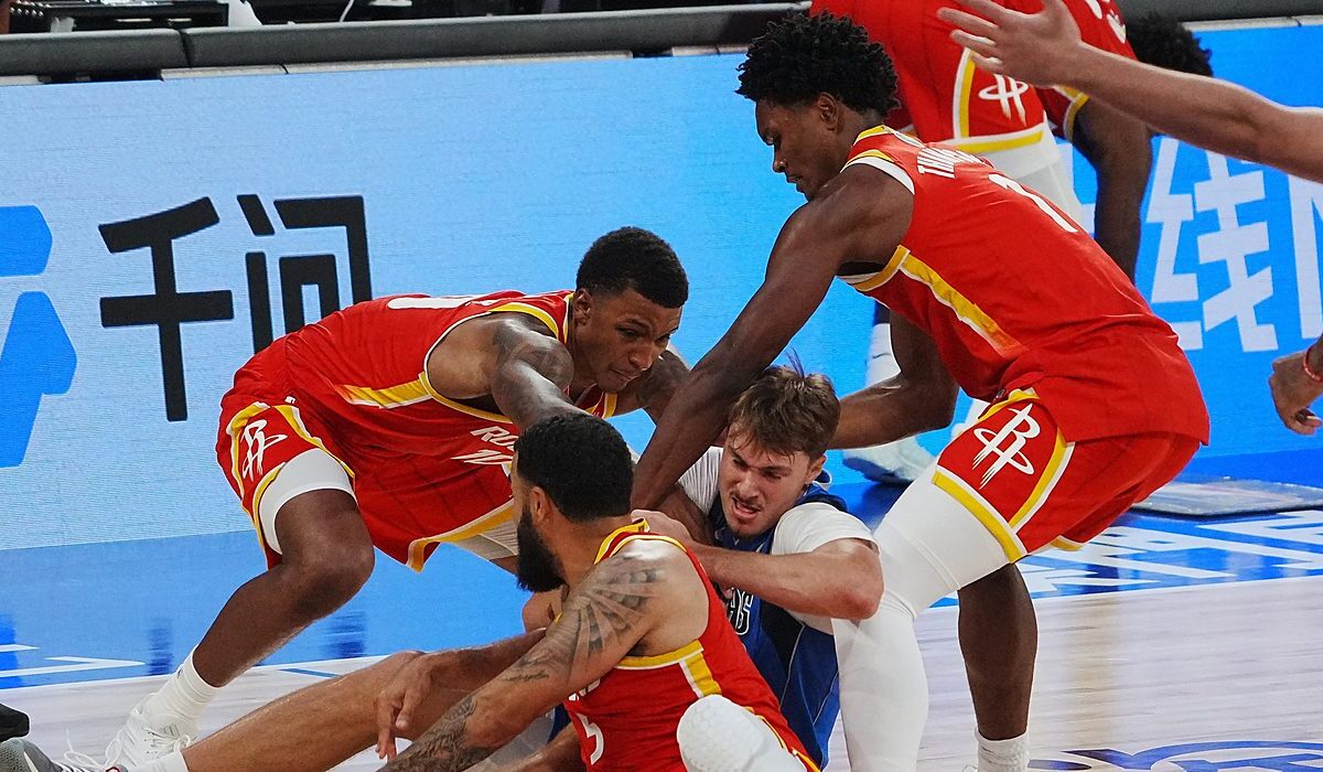 Mavericks forward Cooper Flagg fights for a loose ball on the floor as three Rockets players swarm him.