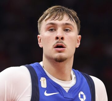Dallas Mavericks forward Cooper Flagg looks ahead with a small gold patch visible above the Nike swoosh on his blue jersey.
