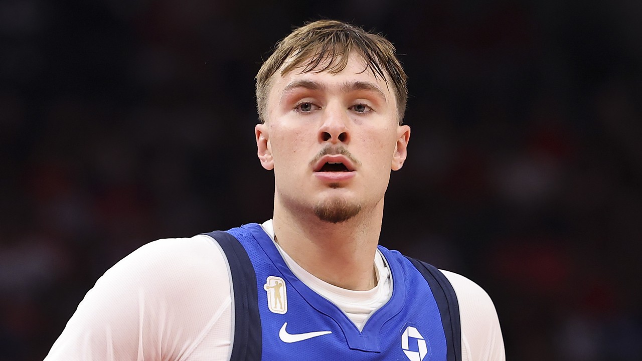 Dallas Mavericks forward Cooper Flagg looks ahead with a small gold patch visible above the Nike swoosh on his blue jersey.
