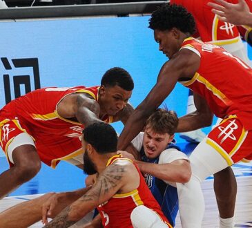Mavericks forward Cooper Flagg fights for a loose ball on the floor as three Rockets players swarm him.