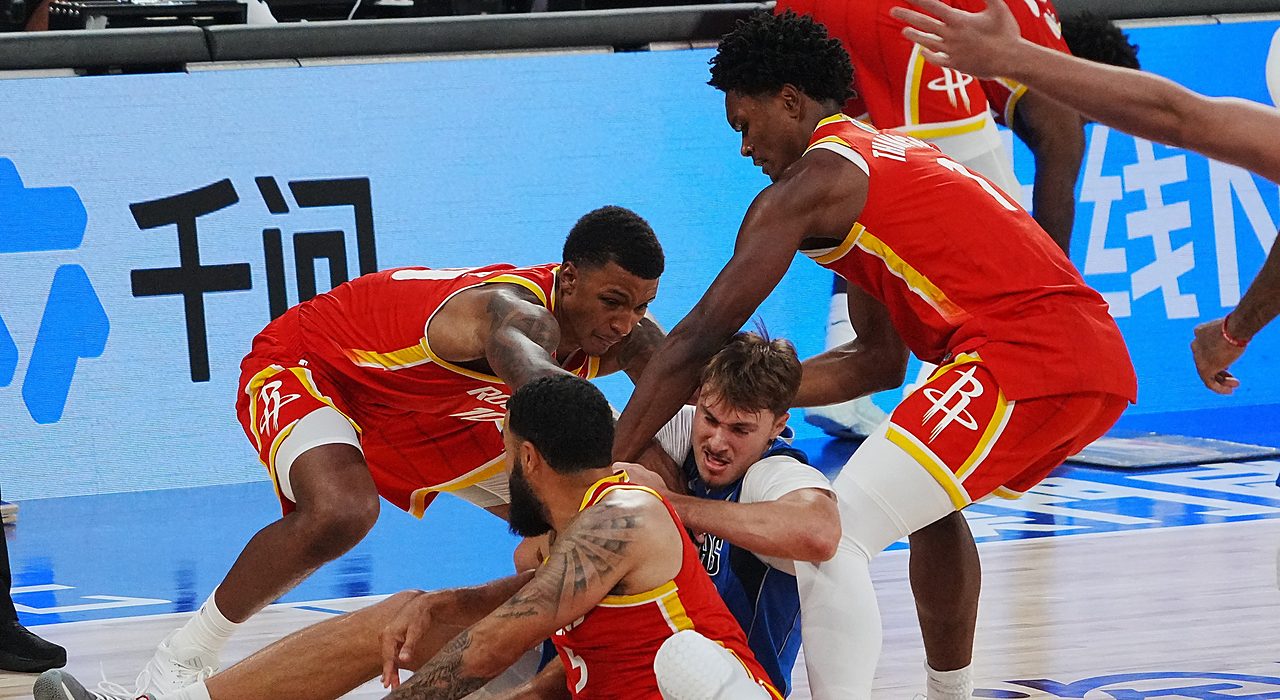 Mavericks forward Cooper Flagg fights for a loose ball on the floor as three Rockets players swarm him.