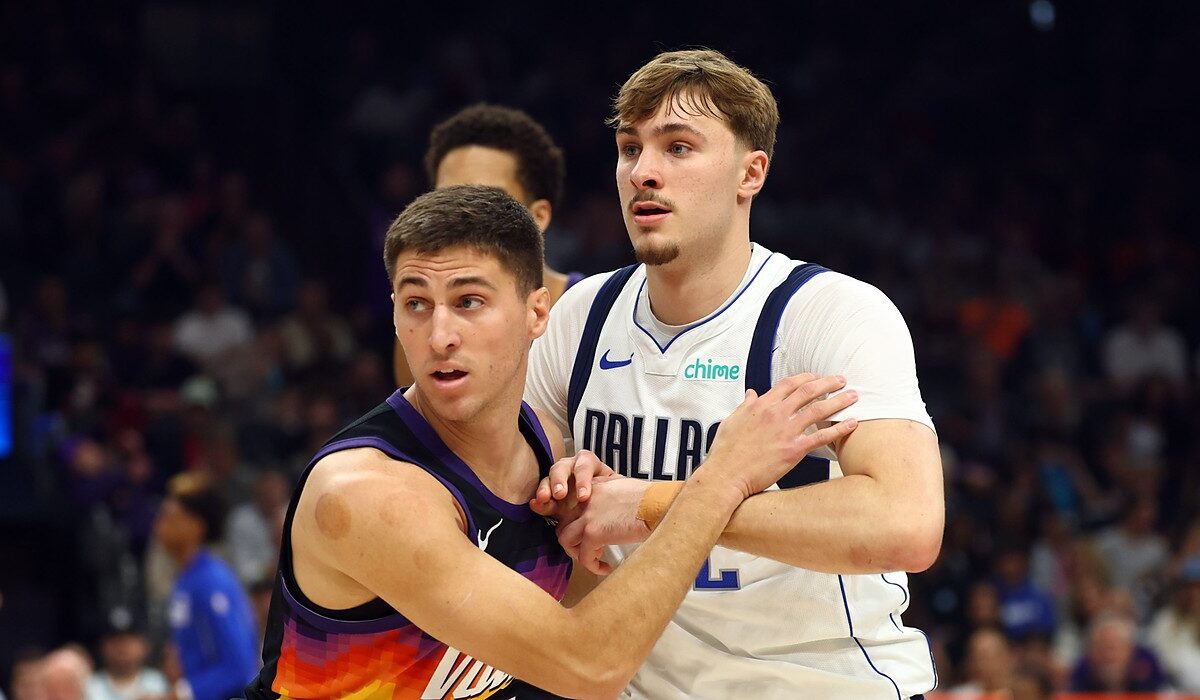 Mavericks forward Cooper Flagg locks arms with Suns guard Collin Gillespie while battling for position.