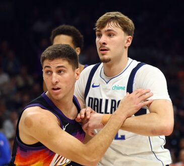 Mavericks forward Cooper Flagg locks arms with Suns guard Collin Gillespie while battling for position.