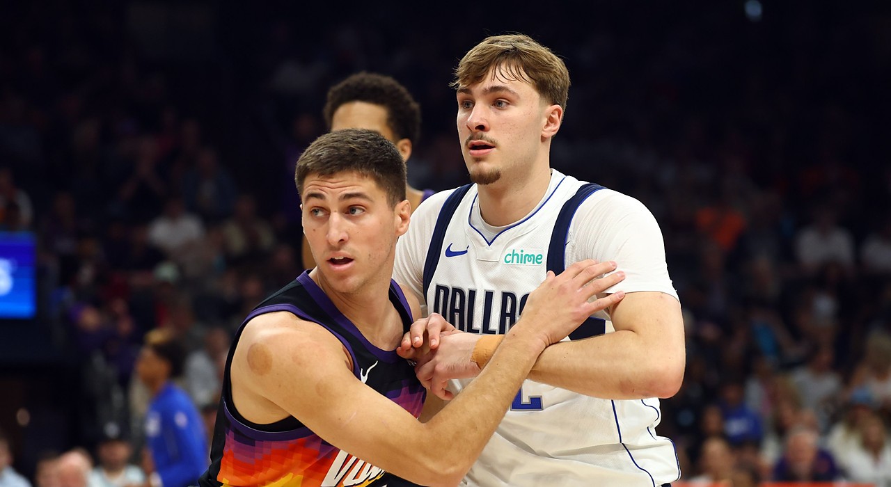 Mavericks forward Cooper Flagg locks arms with Suns guard Collin Gillespie while battling for position.