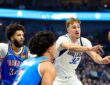 Dallas Mavericks forward Cooper Flagg whips a pass to his left as two Oklahoma City Thunder defenders close in.