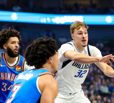 Dallas Mavericks forward Cooper Flagg whips a pass to his left as two Oklahoma City Thunder defenders close in.