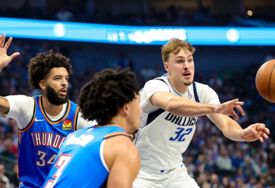 Dallas Mavericks forward Cooper Flagg whips a pass to his left as two Oklahoma City Thunder defenders close in.