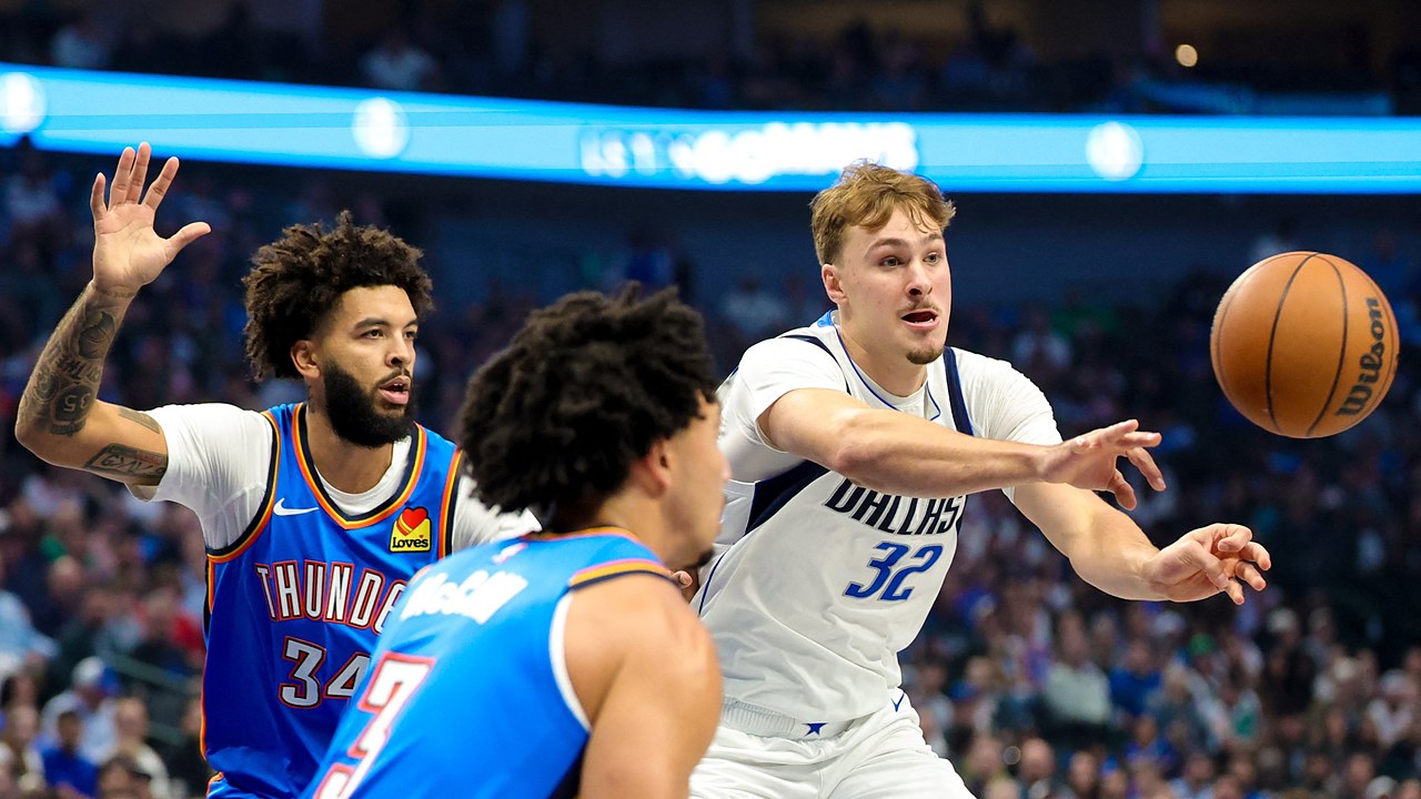 Dallas Mavericks forward Cooper Flagg whips a pass to his left as two Oklahoma City Thunder defenders close in.
