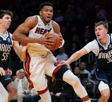 Miami Heat forward Giannis Antetokounmpo drives with the ball between Dallas Mavericks players Sergio de Larrea and Cooper Flagg.