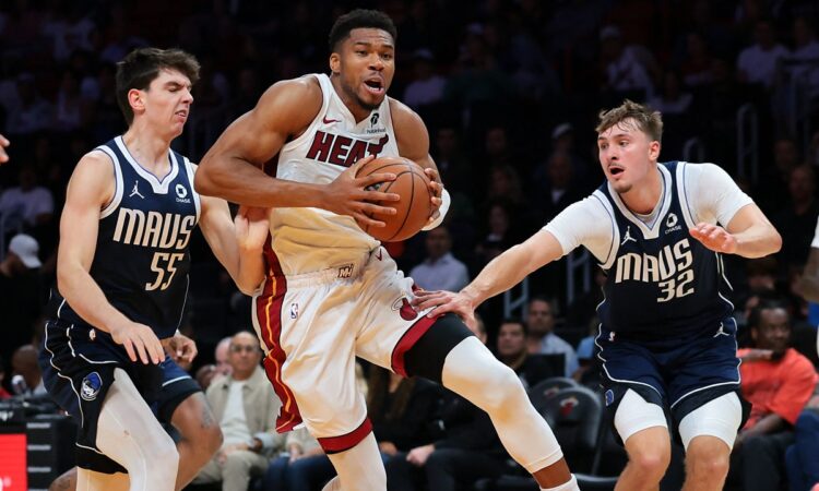 Miami Heat forward Giannis Antetokounmpo drives with the ball between Dallas Mavericks players Sergio de Larrea and Cooper Flagg.