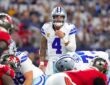 Cowboys quarterback Dak Prescott shouts signals behind the line of scrimmage as linemen crouch in their stances.