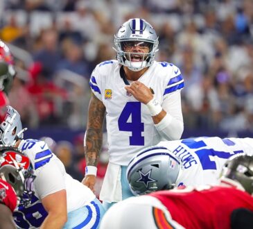 Cowboys quarterback Dak Prescott shouts signals behind the line of scrimmage as linemen crouch in their stances.
