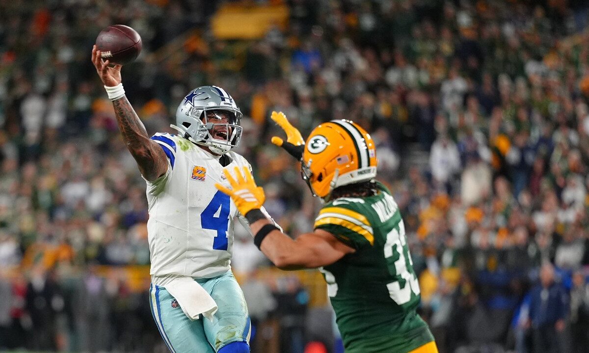 Dallas Cowboys quarterback Dak Prescott throws a pass on the run as Green Bay Packers safety Evan Williams closes in.