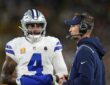 Dallas Cowboys quarterback Dak Prescott talks with head coach Brian Schottenheimer, who wears a headset, on the sideline.