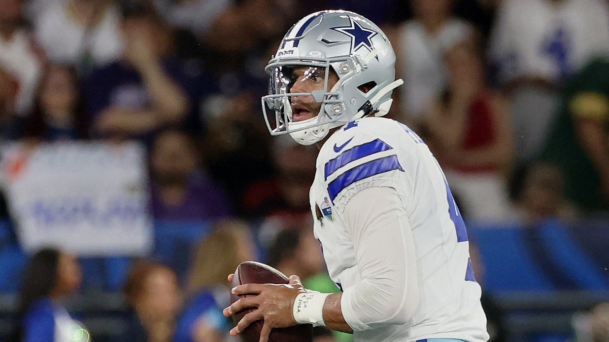 Dallas Cowboys quarterback Dak Prescott holds the ball with both hands while looking downfield.