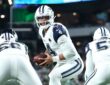 Dallas Cowboys quarterback Dak Prescott turns with the ball in both hands as his offensive linemen block in front of him.